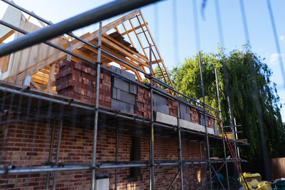Casa em construção com alvenaria e andaimes, imagem ilustrativa